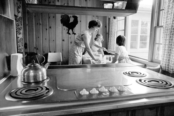 Donna Osness with two of her daughters, preparing dinner for her family. One of a series of images about Donna, a mother of five children, who is participating in a new Madison General School of Nursing program for married women.