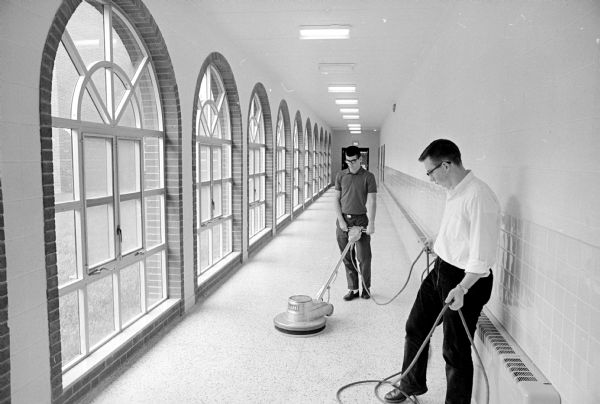 The seminarians at Holy Name Seminary learn that the dignity of manual labor is an important lesson for aspirants to the priesthood. Here Tom Colt, Madison (left), and Allen Faust, Cross Plains, polish the floor in a cloister-like corridor.