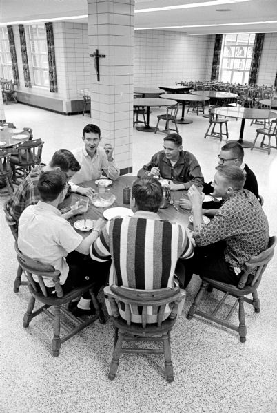 At Holy Name Seminary students are dining at round tables. Sitting with his back to the camera is Tim Terrill, Janesville. Going clockwise around the table are John Freitag, Beloit; David Quick, Beloit; Mike Murphy, Ridgeway; Mark Schumacher, Janesville; Mark Joyce, Bloomington; and Matt Joyce, Endeavor.