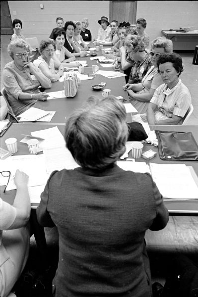 Members of the Madison Chapter of Women in Community Service, Inc. gathered around a long table. They will be conducting screening interviews of applicants for the upcoming Women's Job Corps project and are being briefed by Mrs. Samuel Chartak, Milwaukee, foreground, who is the project coordinator.
