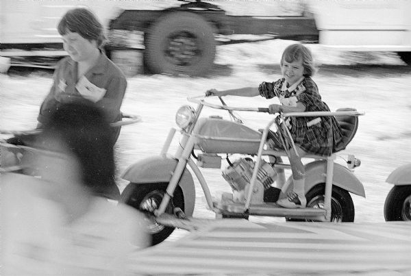 A young girl enjoying a ride during "Kids Day" at the East Side Business Men's Association Festival. About 200 children from Wisconsin Treatment Center, Retardation Clinic, Washington Orthopedic School, and Madison area foster children were treated to free refreshments and rides.