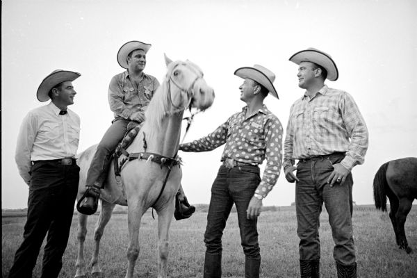 Former heavyweight boxing champion Rocky Marciano on horseback as he prepares for his role as parade marshal in the rodeo at Holmes' No-Oaks ranch. Around him to give advice are, left to right: Jack Snow of Tucson, Arizona, rodeo managing director, and Madison residents George Holmes, master of ceremonies, and Jim Holmes, chute boss.