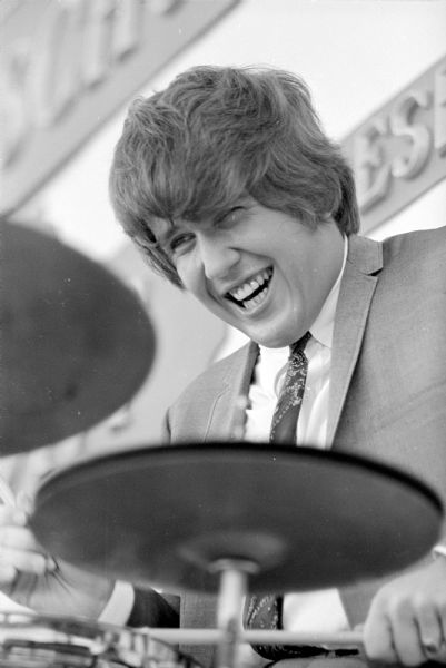 The Beatle-haired drummer from the DuPont dance group band, playing at a pop-concert-fashion show hosted by the Gimbels-Schusters department store, outside the store in the Hilldale Shopping Center. About 1,000 young people attended the event.