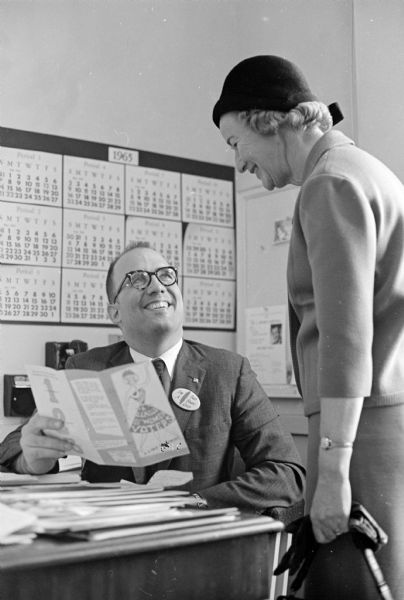 William B. Manchester, public relations director for Harry S. Manchester, Inc., is shown "checking the facts" in a brochure before contributing to the annual League of Women Voters of Madison fund drive.