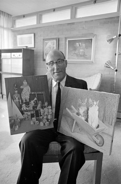 Prize-winning artist, Dr. A.M. Gottlieb (also Director of the Madison Veterans Administration Hospital), is shown with two paintings he created for his grandchildren.
