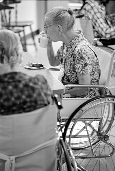 Ella Rodefer is shown in her wheelchair at a table with others during their twice weekly coffee hour and social at the Colonial Manor Nursing Home.