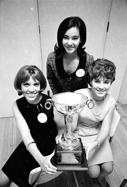 Three of the 20 semi-finalists for the 1965 U.W. Homecoming Queen are shown with the trophy prior to selection. Left to right:  Judy Campbell, Linda Cowan, and Donna Caplan. The decision will be announced October 22.