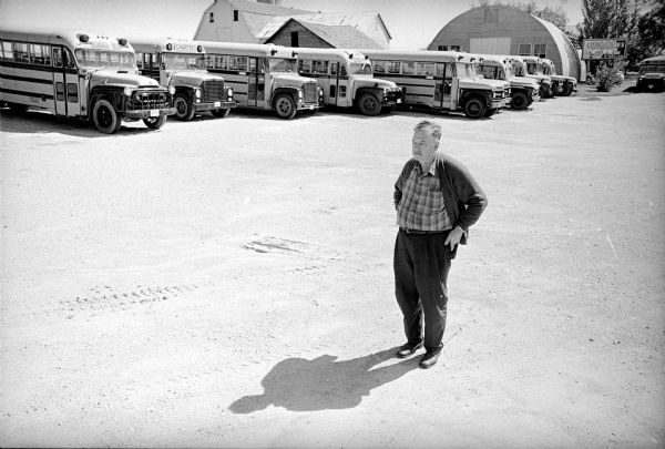 Man standing in front of a row of school buses.