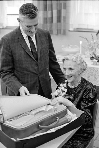 Marguerite Judd is shown opening a gift package at an informal retirement party honoring her 10 year service as a Red Cross volunteer at the Wisconsin Diagnostic Center. Shown looking on is Dr. Robert E. O'Connor, superintendent of the center, who gave tribute to her knack of establishing rapport with young people and her understanding of their emotional problems.