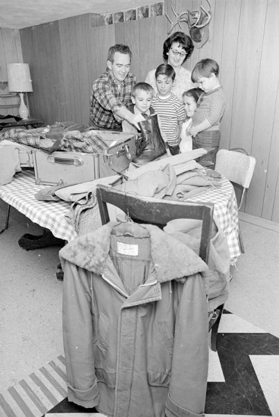 Mr. and Mrs. Richard (Patricia) Cooley, 5106 Sherven Drive. Madison, are preparing for their annual deer hunting trip to the Tomahawk area of northern Wisconsin. Looking on are their children, left to right: Jim, Ricky, Patty and Doreen.