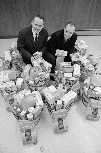 Peter Voeller, secretary treasurer of the Retail Clerks Local 1401, left, and Jack Bretl, labor representative on the United Community Chest are displaying some of the the food baskets the union will distribute to the needy. 
