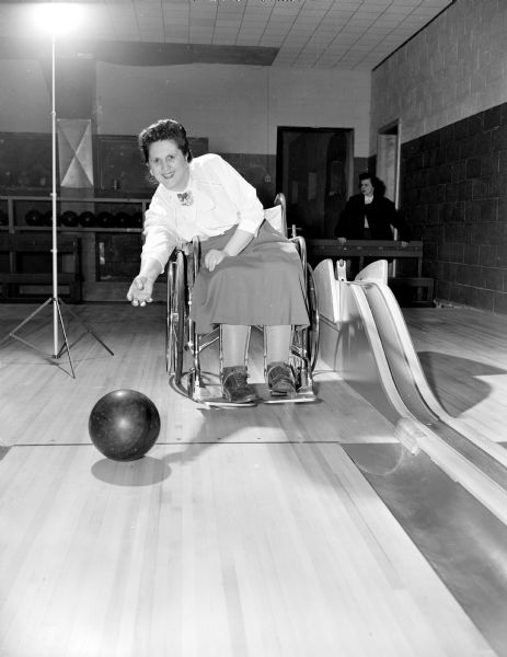 Woman sitting in a wheelchair bowling.