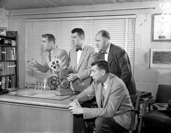 University of Wisconsin football coach, Ivy Williamson, is showing films to Art Lentz, director of the University Sports News Service, boxing coach, Johnny Walsh, and basketball mentor, Bud Foster. The films will be part of a weekly half-hour program on WMTV. Each show will feature film, chalk talks, and question-answer sessions.