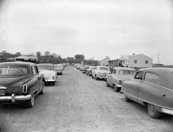 Cars parked along Charles Street (just off Odana Road) where builder B.F. Killian has opened a Show of "Pollman" Homes he has built. 