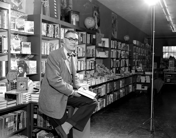 Torrance Graham sitting in front of bookshelves in his book and stationery store in the Shorewood Corners Shopping Center, 3238 University Avenue.