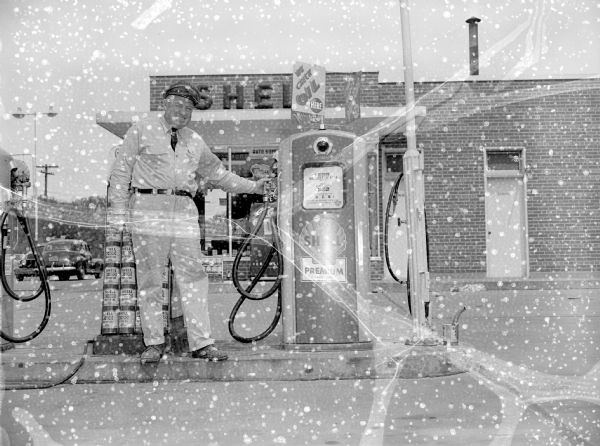 Service station attendant standing next to gas pump at the Shell Gas Station near the Shorewood Corners Shopping Center, 801 Shorewood Boulevard.