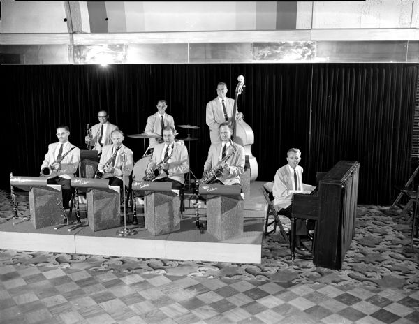 Group portrait of members of the 8 piece Bob Anden Band sitting behind their music stands.