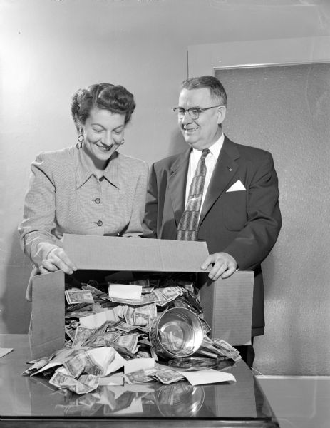 Man and woman looking at a box of money in relation to a WKOW-TV Muscular Dystrophy telethon to raise money for a cure of the disease.