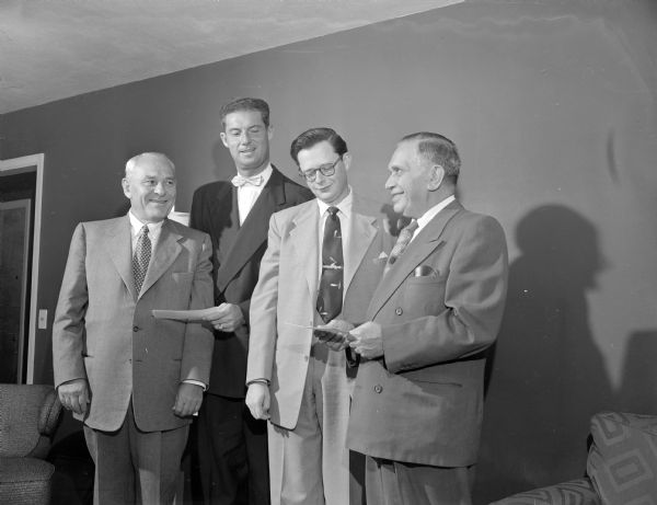 Four men from General Beverage Company holding two checks (?).