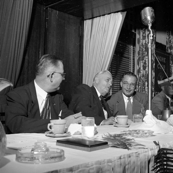 Senator Alexander Wiley chatting with John H. Shiels, vice-president and trust officer with Madison Bank and Trust Company, at the at the luncheon. An unidentified man is on the left and not printed in the newspaper edition.