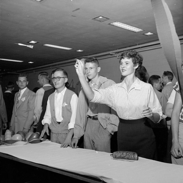 Beverly Thomas, Madison, throwing a dart as Dick Gohdes, Wausau, and others, look on. A series of carnival-like booths familiarized new students with religious and social functions of the Wisconsin Lutheran Student Foundation at an Open House.