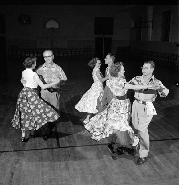 Slightly elevated view of Leonard and Mary Baumann, Harold and Hazel Woods and Mr. and Mrs. Bob Beckman square dancing in the gymnasium at Frank Allis School on Buckeye Road.