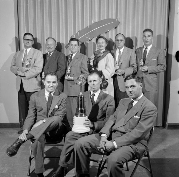 Holding the Chamber of Commerce and Foundation trophy is Leslie Pollard (center front row) of the Business and Industrial Employees Division. Also pictured are Robert Anthony (left) and Stanley Stavrum (right). Six section chairman winners of the Red Father "Oscars" are standing in the back row.