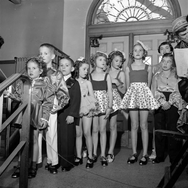 A group of  nine children wearing costumes inside the entrance of the Catholic Center at 15 East Wilson Street.