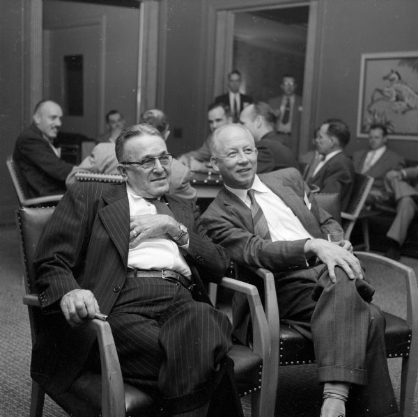 Two attendees listening to a presentation, Fred L. Todd in a pinstripe suit of Madison Vocational School (left), and Dr. A.O. Schmidt holding a drink from Milwaukee (right).