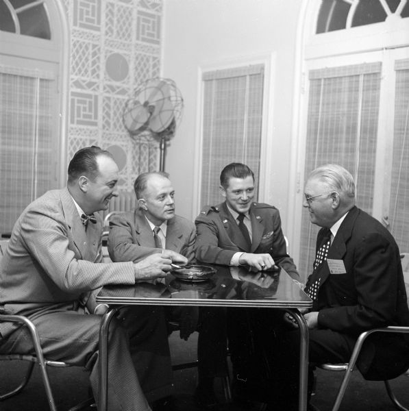 Four men at coffee break at the Maple Bluff Country Club. From left to right are: Jack Murray and A.G. Hoffner from Gisholt Machine Company; Lt. Richard Golden, Truax Field public relations officer; and Woodbridge Bisse from Gisholt Machine Company.