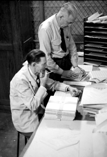 Postal workers, John Hoyt (left) clerk in charge, and Sidney Schoyes, station examiner, are handling stamp requisitions for branch offices and drugstores at the United States Post Office on Monona Avenue.  
