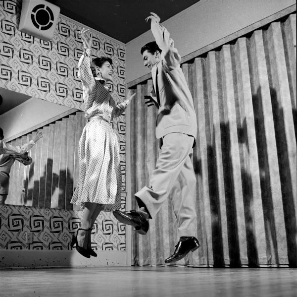 Pauline Keyes and Nick Theiss demonstrating the rumba at the Arthur Murray dance studio. Shadows and reflections accompany their instruction in the mirrored room.