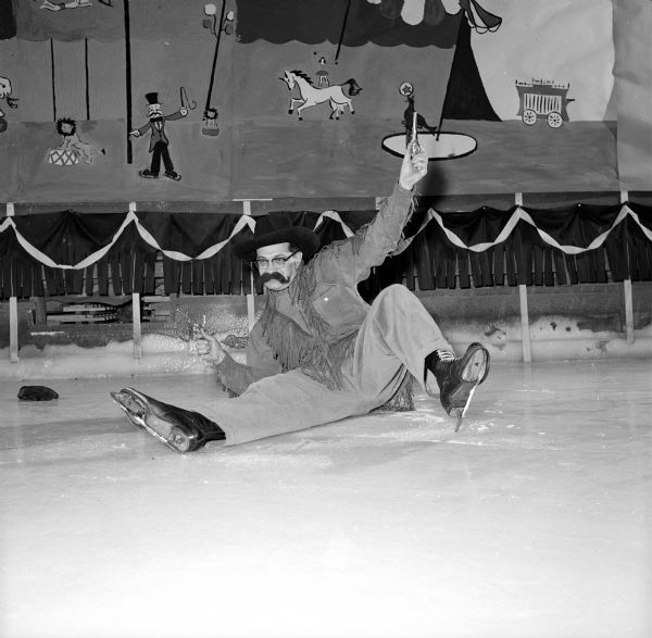 Members of the Madison Figure Skating Club held their annual winter party at the Truax Field Arena. The event was organized on a circus theme. Gordon Sinykin, dressed as a mustached cowboy, is falling on the ice with guns raised high.