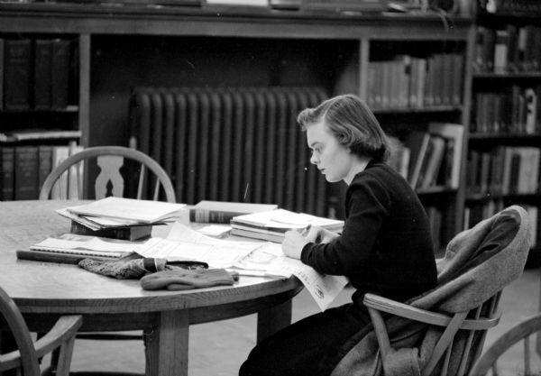 A girl is sitting and working with material in the reference room of the Madison Free Library at 206 North Carroll Street.