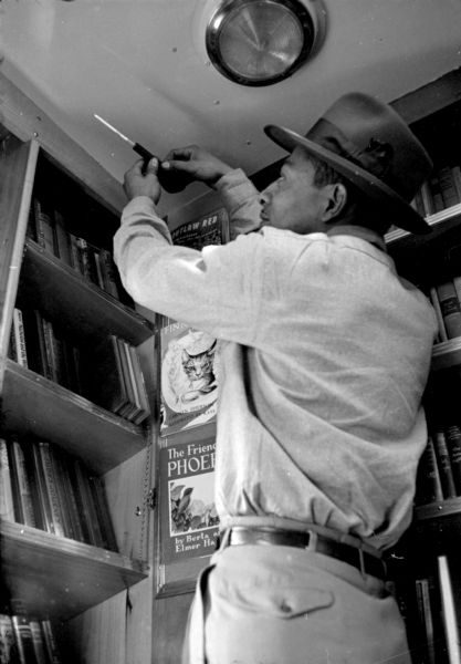 African-American bookmobile driver, Bert Rogers, checking for carbon monoxide in the bookmobile because the motor is kept running for heat. The bookmobile is an outfitted bus.
