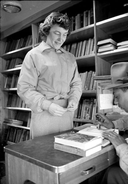 Sylvia Nuckles checking out a book from Bert Rogers, the driver and circulation staff for the Madison Free Library bookmobile.
