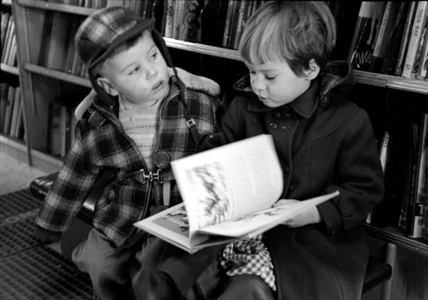 Timmy and Joan Becker are reading a book by the shelves in the Madison Free Library bookmobile, which is parked in the Lakeview Heights neighborhood, a new city housing development.