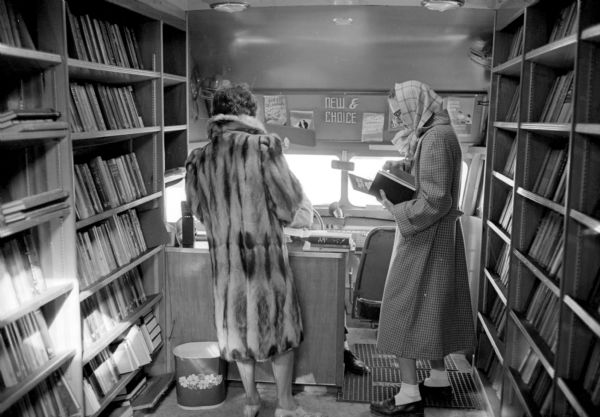 Ruth Culliney and Jeanette Dega browse books on the shelves of the Madison Free Library bookmobile parked in the Lakeview Heights neighborhood, a new city housing development.