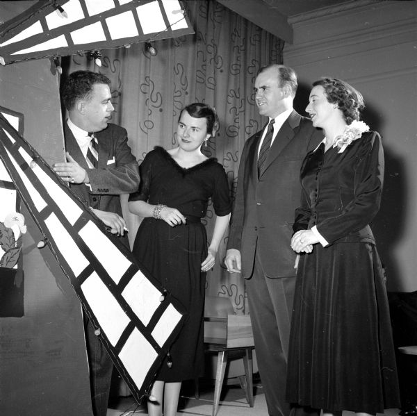 Looking at the windmill decoration at the Panhellenic Ball in Memorial Union's Great Hall are (left to right): Thomas Murphy (general chairman of the ball), Joan Fagen, and her parents, Joseph C. and Mary Fagen (who were chaperones). Mrs. Fagen is wearing a corsage.