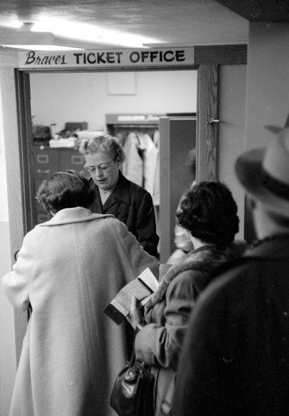 Mrs. Paul Hilgers of Middleton selling tickets for Milwaukee Braves baseball games at the branch ticket office in the basement of The Hub clothing store in downtown Madison.