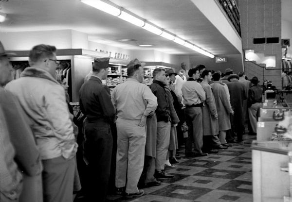 View down the line of people waiting to buy tickets for Milwaukee Braves baseball games at The Hub clothing store in downtown Madison, where the branch ticket office is located.