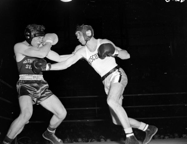 Don Backus (of Washington State) winces as Bob Meath of the University of Wisconsin punches right from the start of the bout.