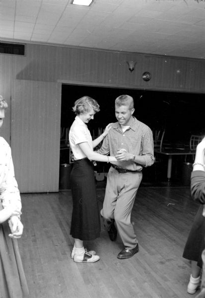 The Shorewood Hills Community League sponsored a dance class for teenagers at the Blackhawk Country Club that was taught by Arthur Murray instructors. Julie Dunn, wearing saddle-horn shoes and white bobby socks, is watching Fred Mohs' dancing feet.