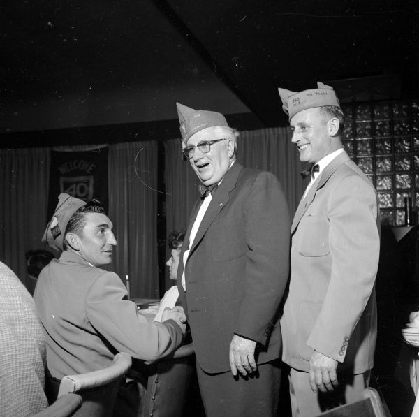 Victor Weisensel (of Sun Prairie), Leo R. Mullarkey (of Madison), and Harry C. Miller (of Sun Prairie) reminisce, during the banquet of the Annual Dane County American Legion 40-and-8 banquet. The title for this legion group comes from box cars used  during World War I to transport troops to the front line in France: They would carry forty men or eight horses.