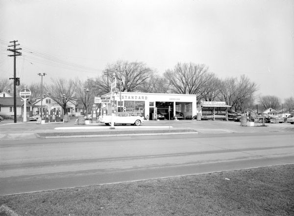 Harvey's Standard Service Station located at 2602 East Washington Avenue (at North Street), featuring their dealership of Atlas tires. A car is pulled up at one of the fueling pumps.