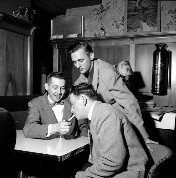 Executive Chef, Warren Olsen (left) lighting a cigarette for Bryce Amunson of Wisconsin Rapids, while David Botham is looking on. Amunson and Botham are students at the vocational school. The men were attending a Restaurant Group meeting at Minnick's Top Hat located on University Avenue at Branch Street.