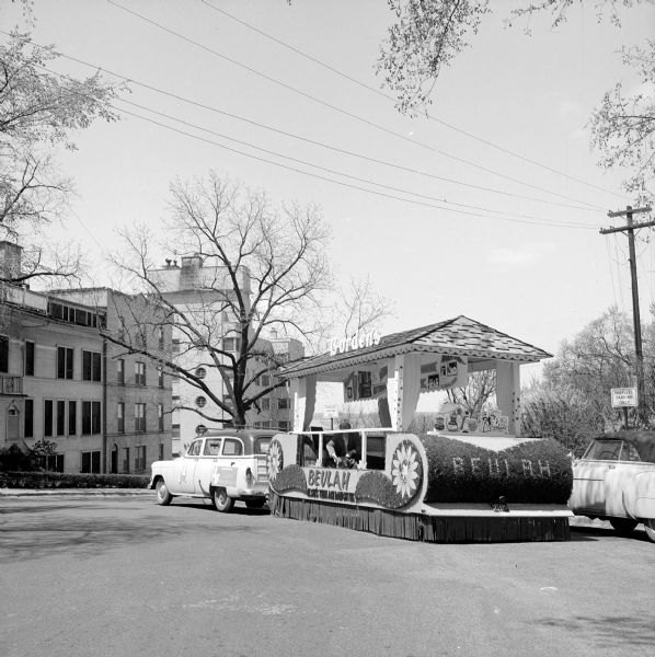 Station wagon pulling a float for Borden's Dairy on a trailer at the Governor's luncheon for the Dairy Foods Festival held at the Edgewater Hotel. The float is for "Beulah the Cow," who was the cartoon calf of Borden's Elsie the Cow and Elmer the Bull.