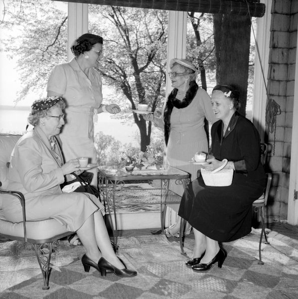 Four Republican club women are shown having punch at the Republican Centennial Birthday Party and membership tea held by the Dane County Women's Republican Club. Shown left to right are: Mrs. H.B. Rue, Mrs. Leonard Peterson of Mount Horeb, Mrs. Harry Keenan and Mrs. Harry C. Chapin. One of the Madison lakes is in the background.