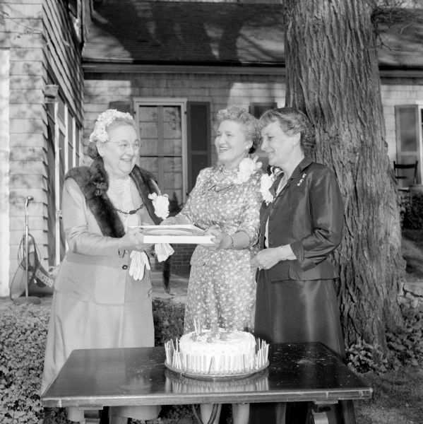 Women attending the Republican Centennial Birthday party. Because the party fell on the same date as Mrs. Paul Irwin's (left) 75th birthday, she was presented with a surprise birthday cake. At center and right, are Mrs. Francis Lamb, president of the Dane County Republican club; and Mrs. Thomas Coleman, the tea hostess.