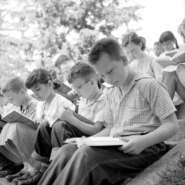 Pupils reading <i>Days of Adventure</i> outdoors: Lucy Hobbins, Dennis Curran and Carlton Enger.